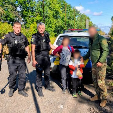 Врятований хлопчик з поліцейськими на фоні автомобіля поліції